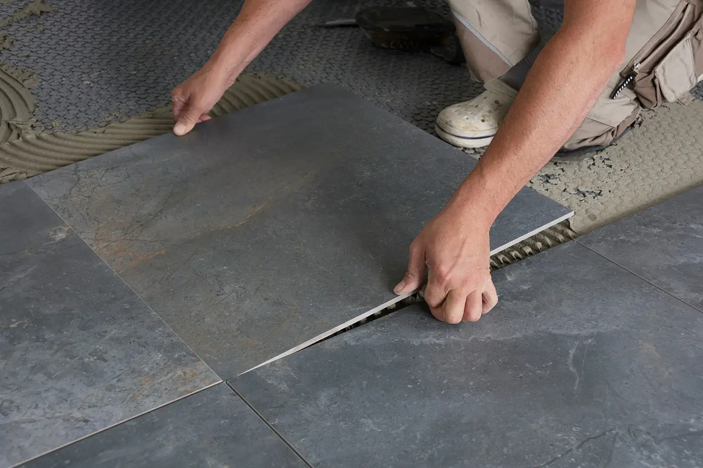 Ein Arbeiter beim Verlegen von Bodenfliesen