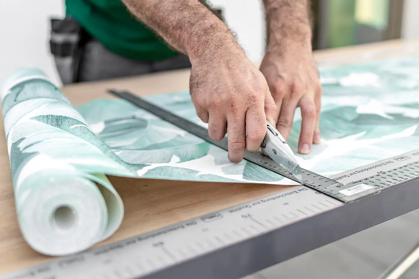 Zuschneiden einer Tapete mit modernem Blattmuster