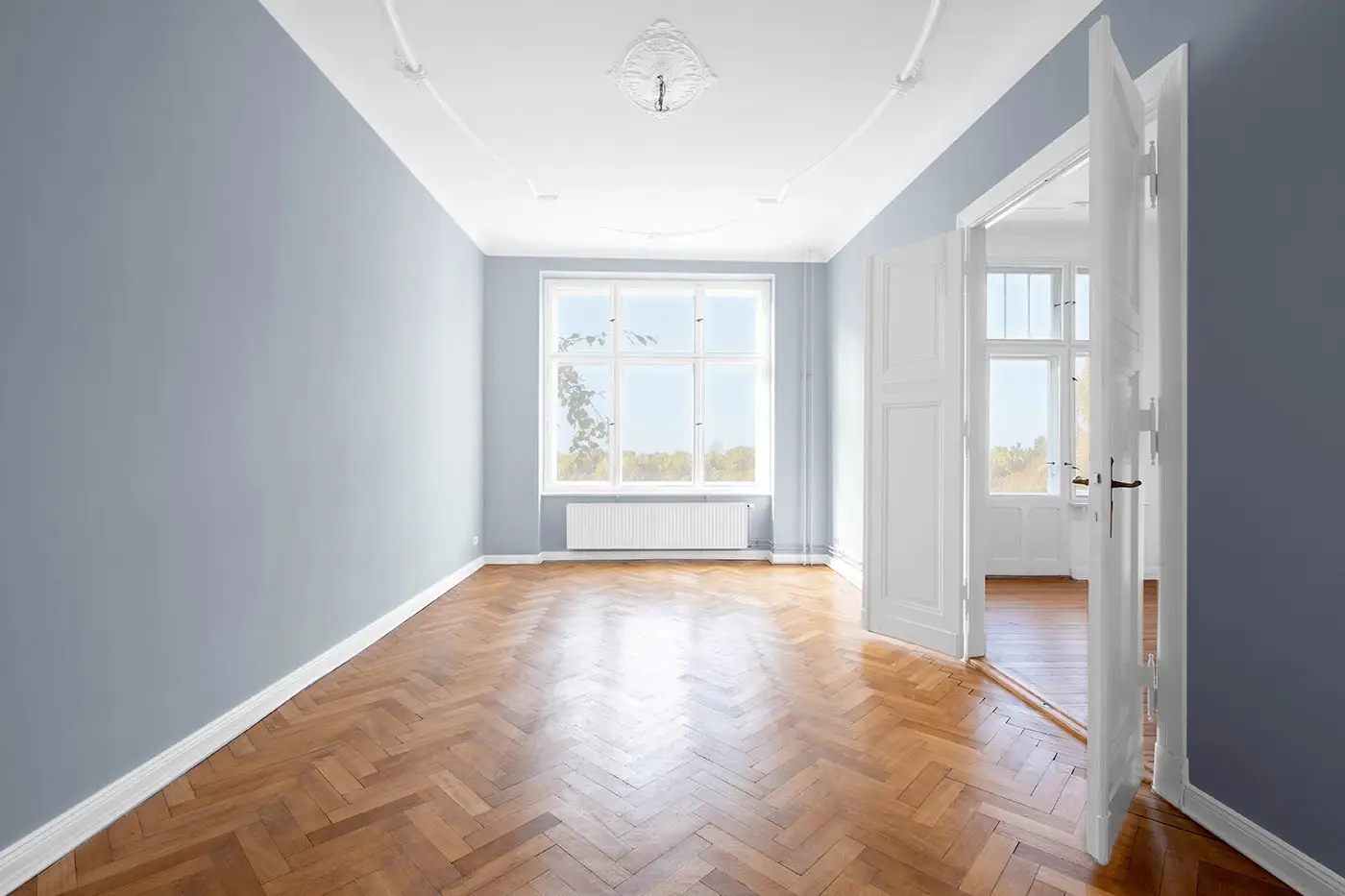 Blick in ein frisch gestrichenes Zimmer in hellblaugrau mit weißen Akzenten