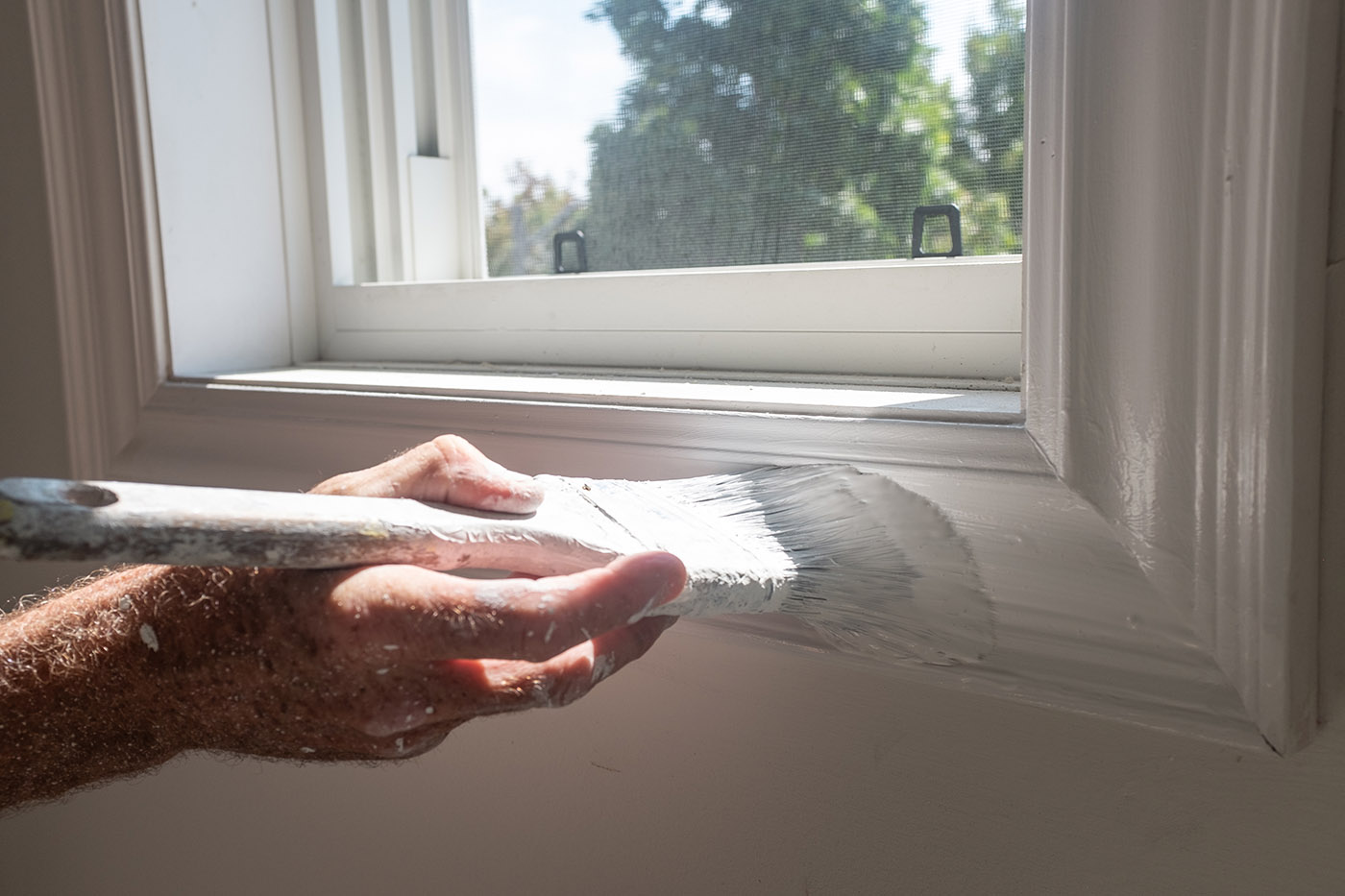 Ein Maler lackiert einen Fensterrahmen