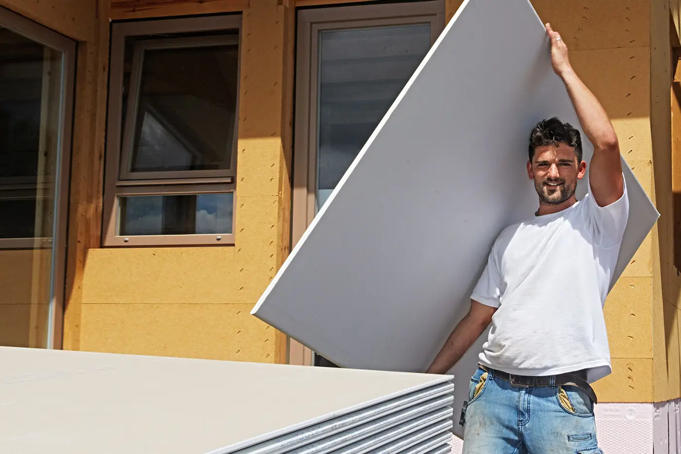 Ein Arbeiter trägt eine Platte für den Trockenbau