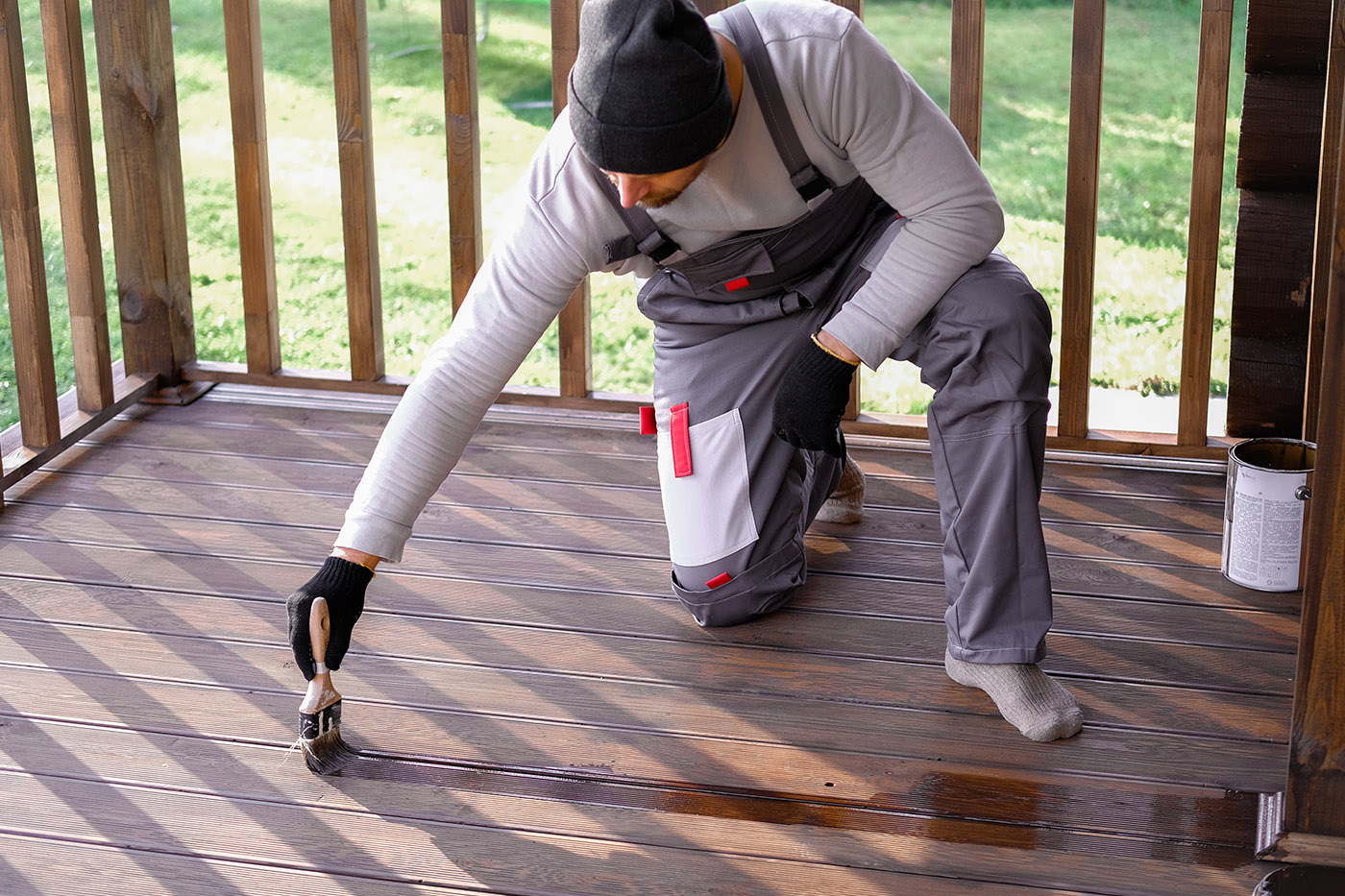 Ein Maler lackiert den Holzfußboden einer Terrasse