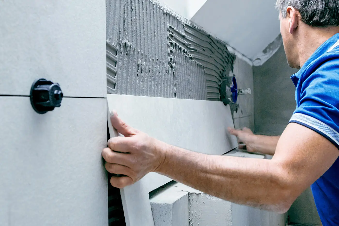 Arbeiter bei der Anbringung einer zugeschnittenen Fliese über einem Spülkasten
