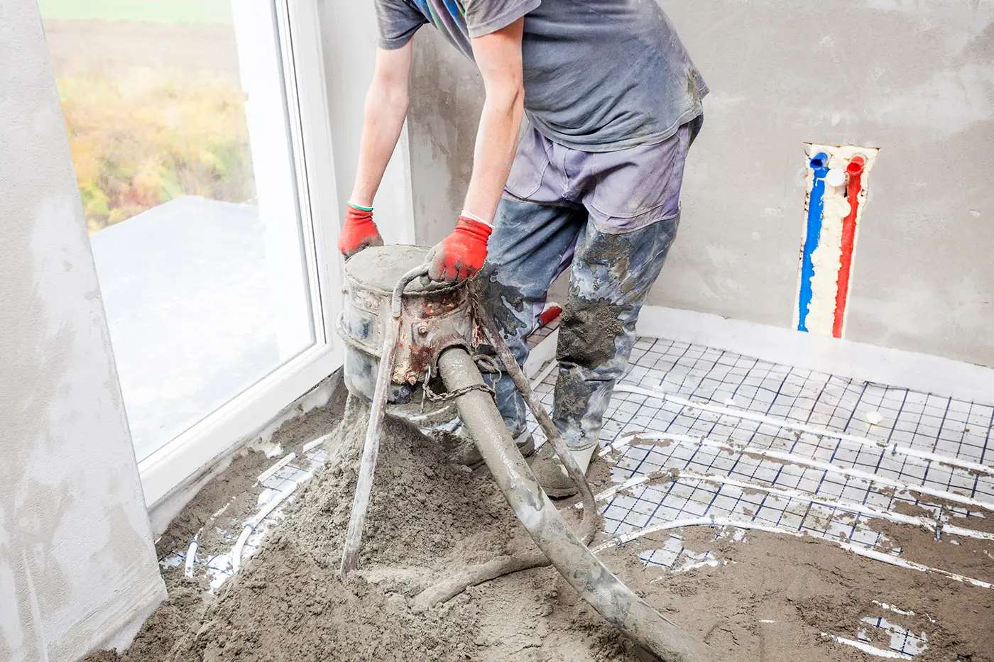 Arbeiter mit Estrichmaschine über Fußbodenheizung