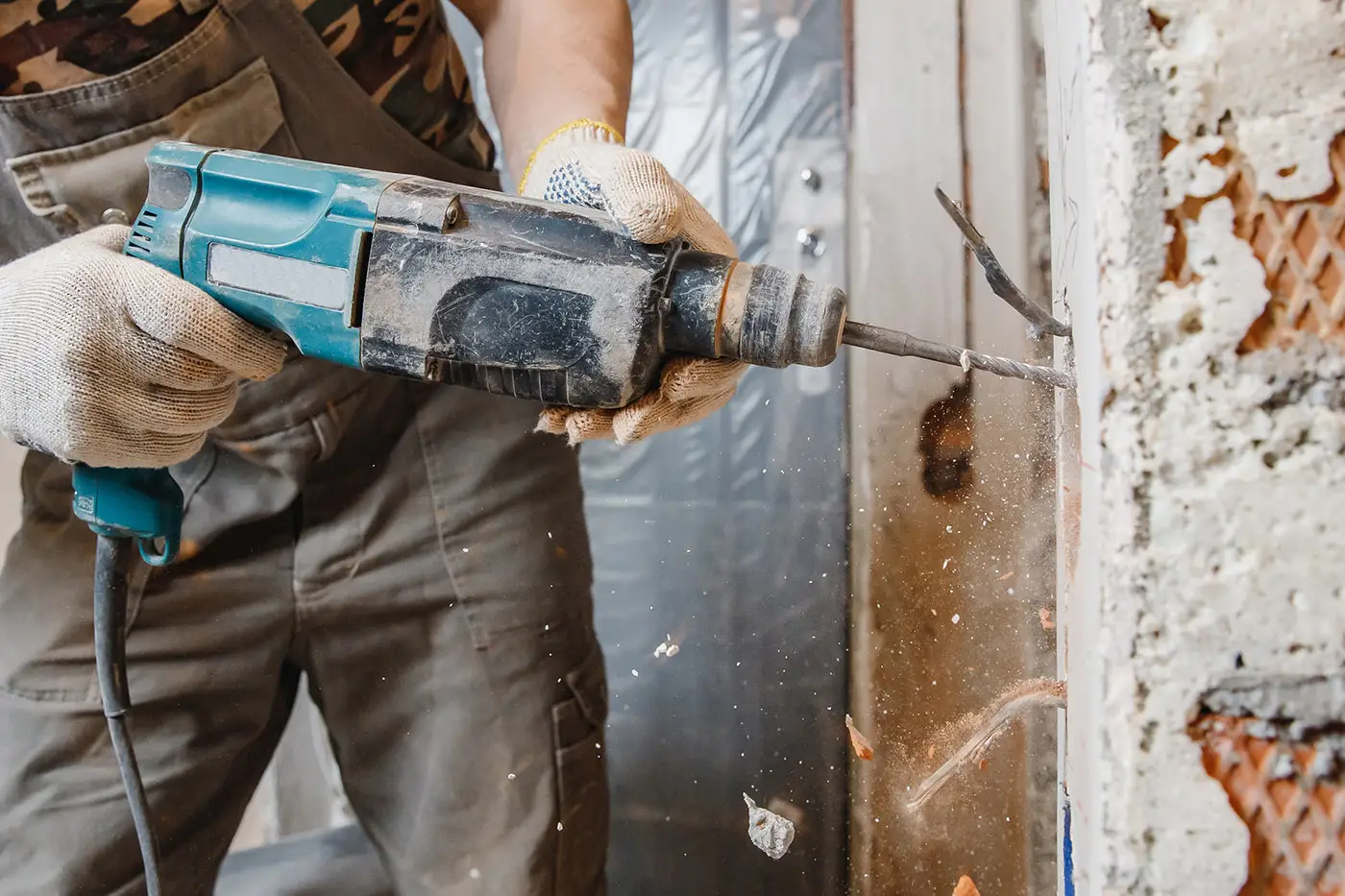 Ein Arbeiter mit Bohrmaschine bei der Sanierung einer Wand