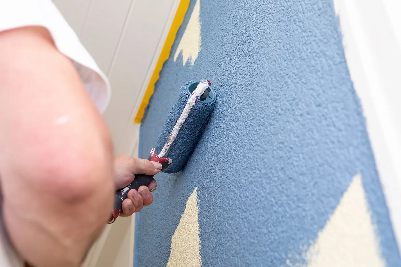 Ein Maler streicht eine Wand in blauer Farbe