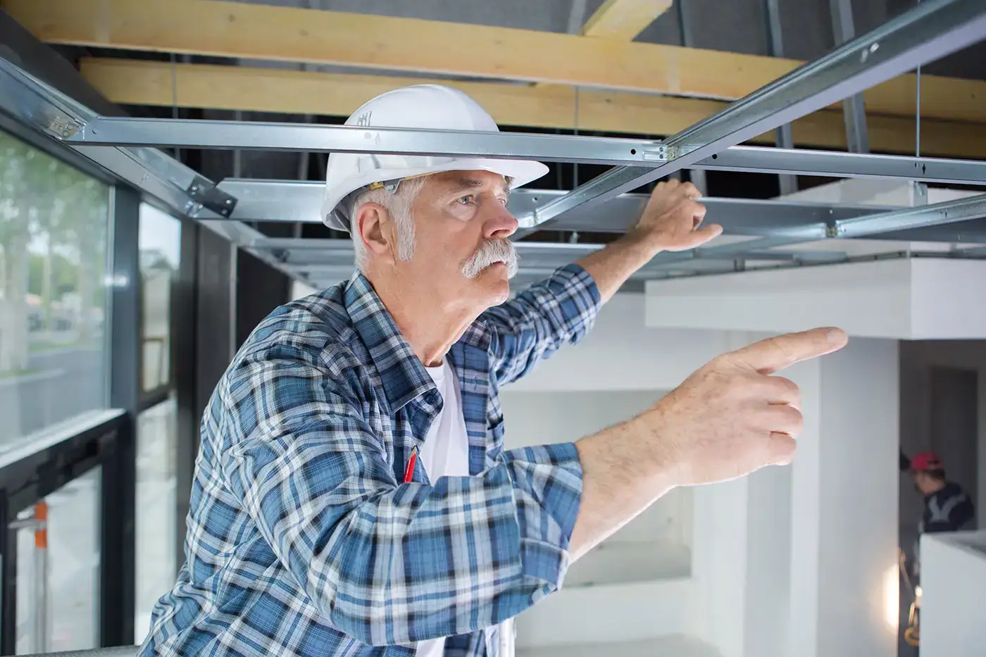 Handwerker mit Bauhelm begutachtet Wasserschaden an der Deckenkonstruktion