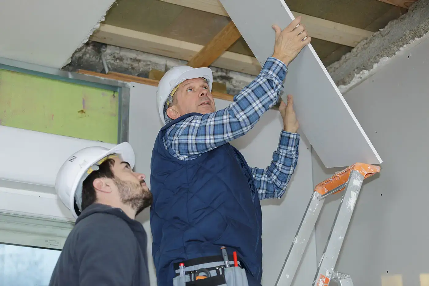 Handwerker arbeiten an Wasserschaden an der Deckenkonstruktion