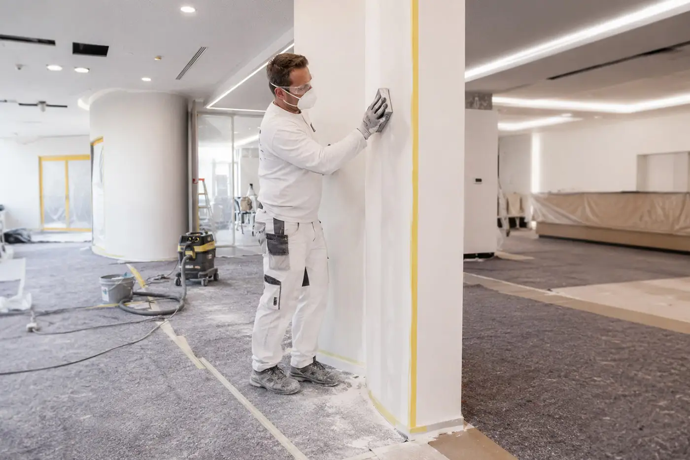 Handwerker bei Schleifarbeiten an einer Wand