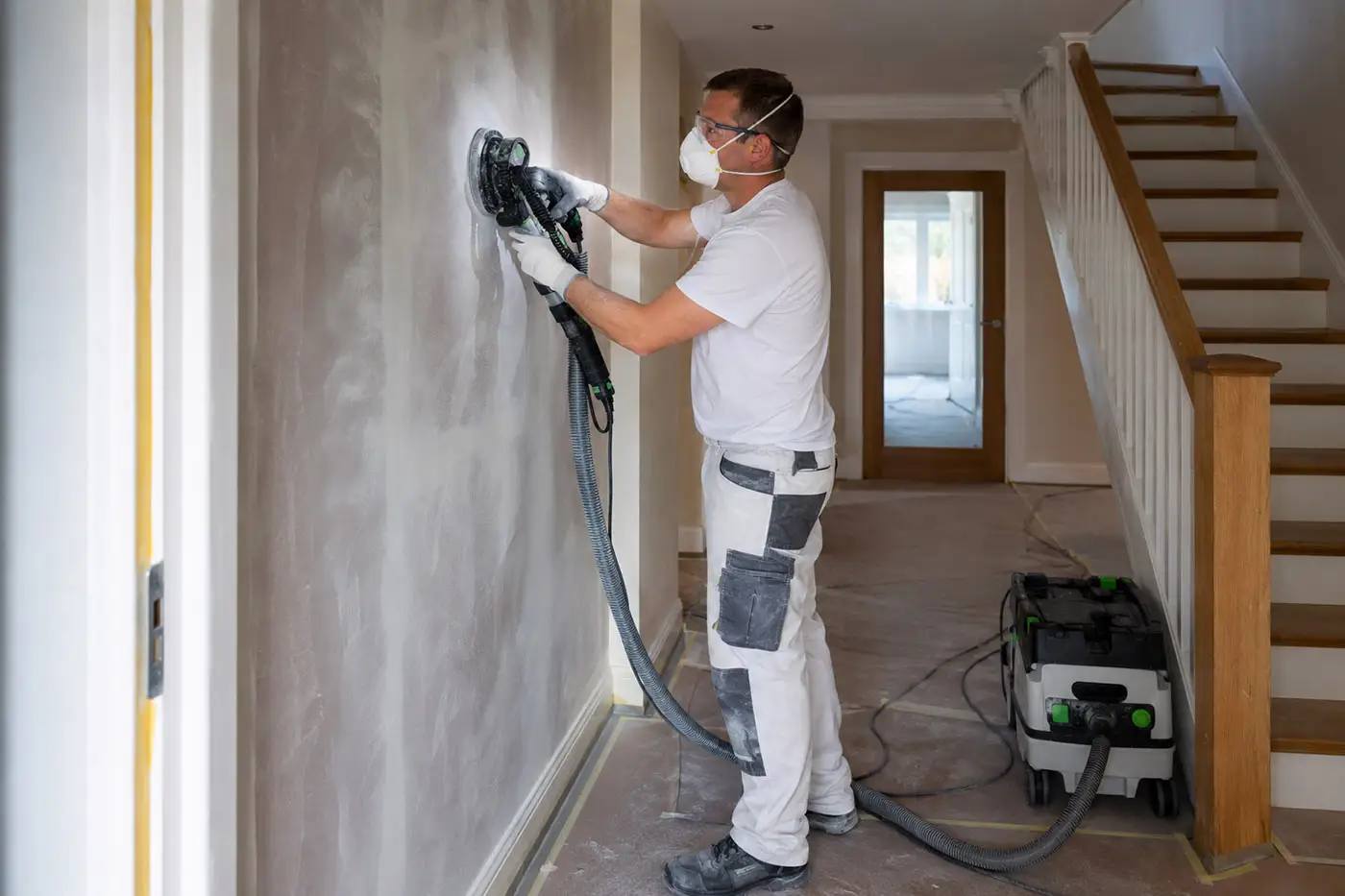 Handwerker bei Schleifarbeiten an einer Wand