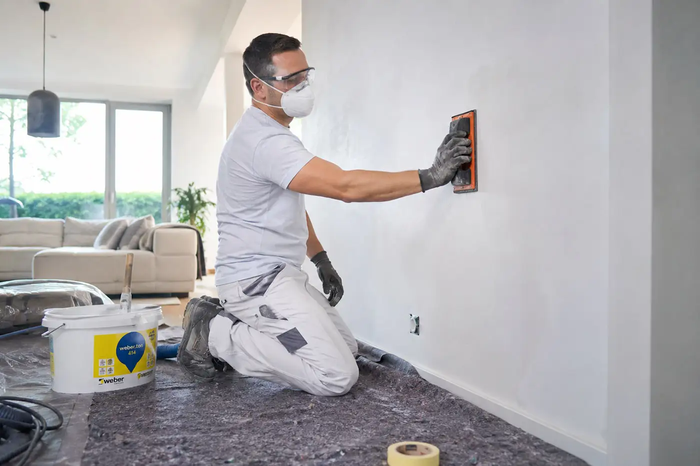 Handwerker bei Schleifarbeiten an einer Wand