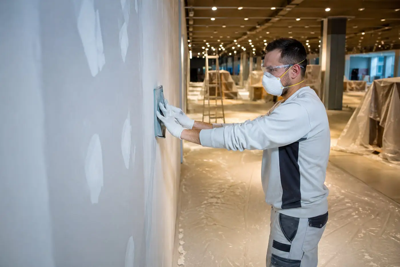 Handwerker bei Schleifarbeiten an einer Wand